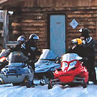 A group of snowmobilers rest in from of Red Rock Lake Shelter.