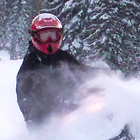A woman gets snow in her face while snowmobiling near Fernie, BC