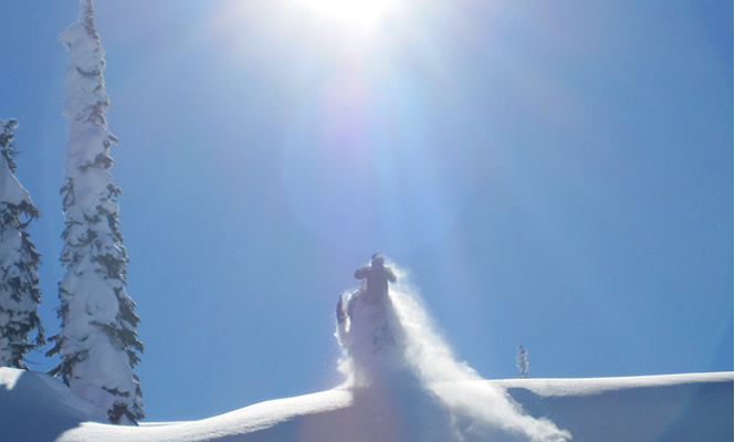 man riding a sled over a hill with sun in the background