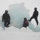 Three men next to an iceberg